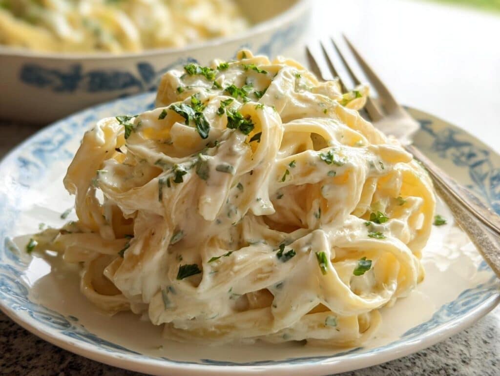 Close-up of creamy Boursin Pasta Bake featuring fettuccine coated in a rich white sauce and topped with fresh chopped parsley.