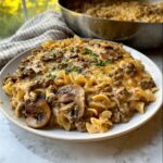 A plate piled high with Creamy Mushroom Ground Beef Casserole featuring egg noodles, ground beef, and melted cheese.