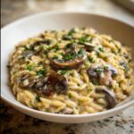 A close-up, appetizing shot of rich Creamy Mushroom Orzo topped with sautéed mushroom slices and fresh parsley.