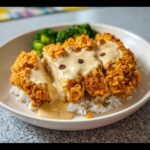 Close-up of Crispy Garlic Chicken Cutlets sliced and drizzled with creamy garlic sauce, served over white rice with broccoli.