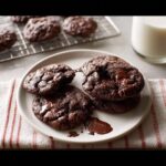 A stack of rich, dark Double Chocolate Espresso Cookies with melted chocolate pools on a white plate.