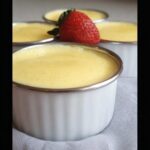 Close-up of creamy Easy TM6 Vanilla Custard Pots in white ramekins, garnished with a fresh strawberry.
