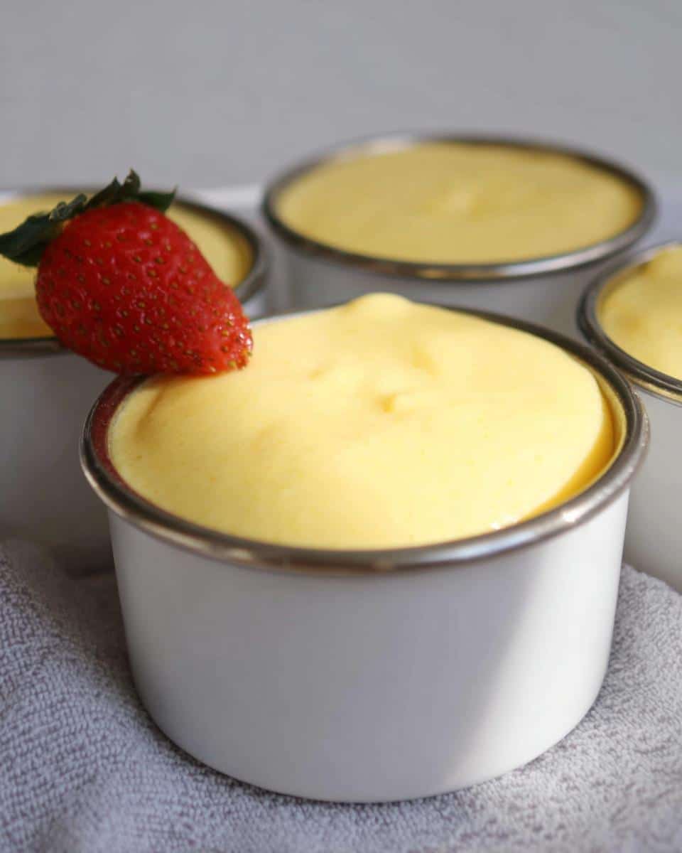 Close-up of creamy Easy TM6 Vanilla Custard Pots topped with a fresh strawberry.