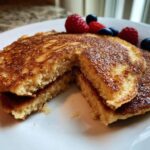 Close-up of fluffy Keto Almond Flour Pancakes cut in half, showing the interior texture and berry topping.