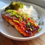 A perfectly cooked fillet of Gochujang Honey Roasted Salmon glazed with a spicy-sweet sauce, served with white rice and steamed broccoli.
