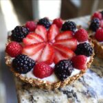 A single, beautiful Greek Yogurt Berry Tart Cup topped with sliced strawberries, raspberries, and blackberries.