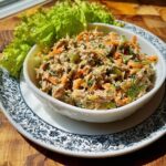 A white bowl filled with Greek Yogurt Tuna Bowl salad mix, featuring shredded carrots and celery.