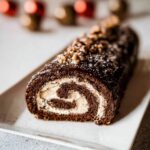 A close-up of the sliced Hazelnut Praline Yule Log Roll showing the chocolate sponge and creamy filling.