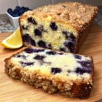 Close-up of a slice of Keto Blueberry Breakfast Loaf showing moist crumb, blueberries, and a thick streusel topping.