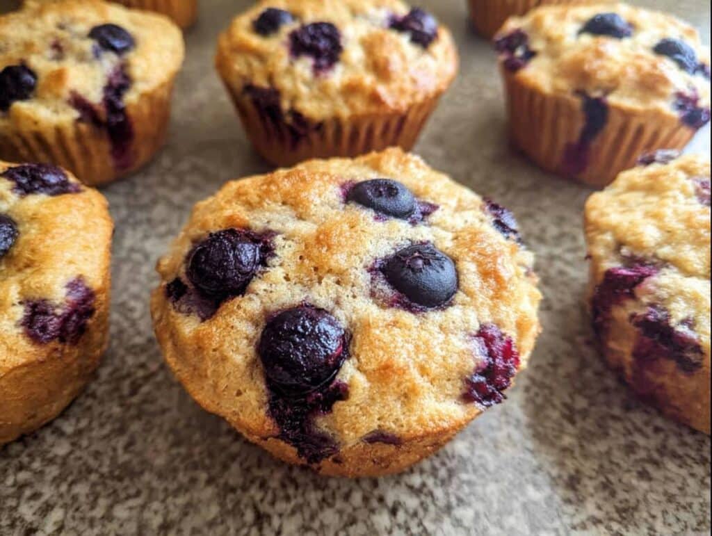 Close-up of freshly baked Keto Coconut Flour Muffins topped with whole blueberries.
