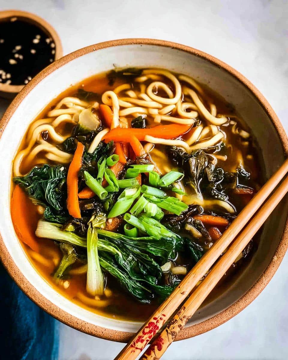 Overhead view of a steaming bowl of Miso Vegetable Soup featuring noodles, bok choy, carrots, and green onions.