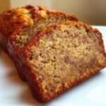 Close-up of two thick slices of moist Vegan Banana Bread Without Eggs on a white plate.