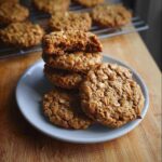 A stack of freshly baked Oatmeal Peanut Butter Cookies on a small grey plate, one cookie is broken open showing the soft center.