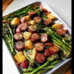 Roasted sausage slices, potatoes, and asparagus for a Quick Sausage & Veggie Sheet Pan Dinner on a metal tray.