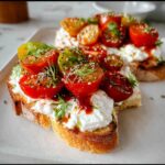 Close-up of Savory Cottage Cheese Toast topped with halved cherry tomatoes, herbs, and seasoning.
