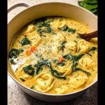 Close-up of creamy Spinach & Cheese Tortellini Fall Soup filled with tortellini, spinach, and grated Parmesan cheese.