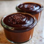 Two servings of rich Thermomix Chocolate Pots de Crème topped with dark chocolate ganache and crumbles.