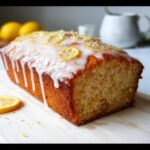 A whole Thermomix Lemon Loaf with Glaze, topped with white icing, candied lemon slices, and zest.