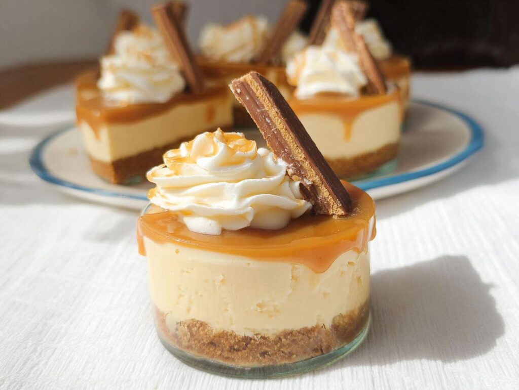 Close-up of an individual Thermomix Salted Caramel Cheesecake topped with whipped cream, caramel drizzle, and a chocolate wafer.