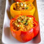 Close-up of bright red and orange Tuna Stuffed Bell Peppers filled with a savory mixture and topped with herbs.