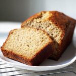 Close-up of a loaf of 2-Banana Easy Banana Bread, with one thick slice cut and leaning against the main loaf.