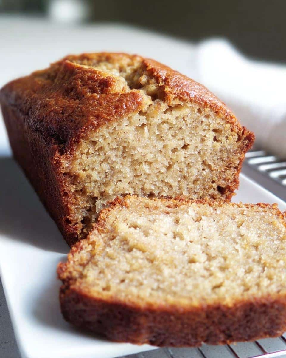 Close-up of a loaf of 2-Banana Easy Banana Bread with one thick slice cut and resting against the main loaf.