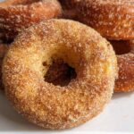 A stack of freshly Baked Cinnamon Sugar Donuts heavily coated in sparkling cinnamon sugar mixture.