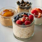Close-up of High-Protein Overnight Oats topped with fresh blueberries, raspberries, strawberries, and a drizzle of honey.