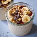 Close-up of Blended Overnight Oats topped with banana slices, peanuts, chocolate chunks, and caramel sauce.