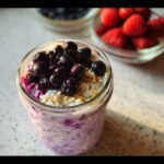 Close-up of overnight oats with cottage cheese topped with fresh blueberries in a jar.