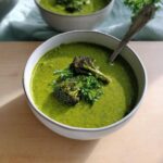 Close-up of a vibrant Broccoli Spinach Green Soup garnished with roasted broccoli florets and parsley.
