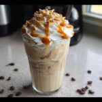 A tall glass of blended Caramel Cookies n Cream Drink topped with whipped cream, caramel drizzle, and cookie crumbs.