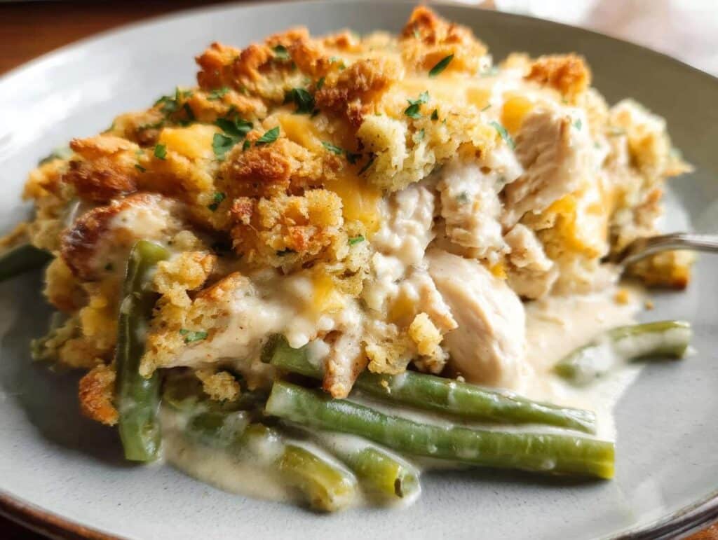 A close-up serving of Chicken and Stuffing Casserole featuring creamy chicken, green beans, and a golden, crispy stuffing topping.