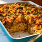 A serving dish of Chicken and Stuffing Casserole with Gravy, showing shredded chicken and a golden, crispy stuffing topping.