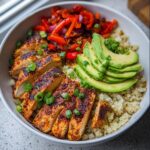 Close-up of a Chicken Cauliflower Rice Bowl featuring seasoned sliced chicken, avocado, and sautéed peppers.