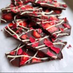 Close-up of broken pieces of Chocolate Covered Strawberry Bark topped with fresh and freeze-dried strawberries.