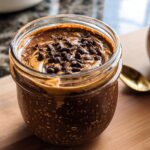 Close-up of Chocolate Peanut Butter Overnight Oats topped with chocolate chips in a glass jar.