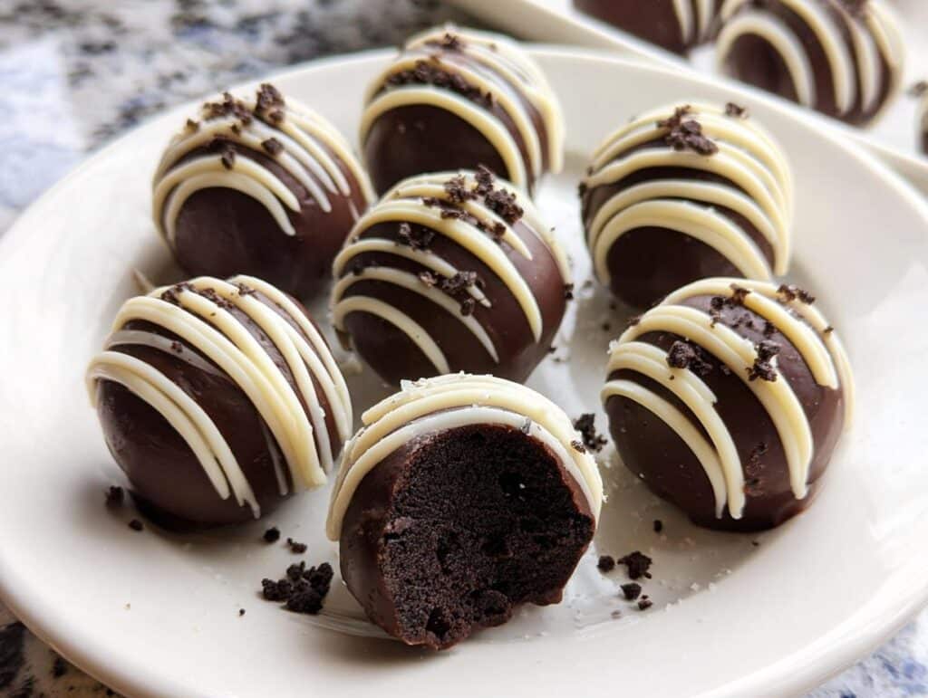 Several decadent Classic No-Bake Oreo Balls dipped in dark chocolate, drizzled with white chocolate, and sprinkled with crumbs.