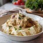 A serving of Creamy Garlic Chicken Over Mashed Potatoes topped with rich sauce and parsley.