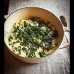 A creamy bowl of White Bean Kale Soup, rich with dark green kale and topped with fresh herbs.