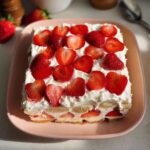 A layered Easy Strawberry Banana Pudding dessert topped with whipped cream and fresh sliced strawberries.