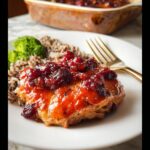 A plated serving of Fall Chicken Casserole topped with a bright cranberry glaze, served with rice and broccoli.