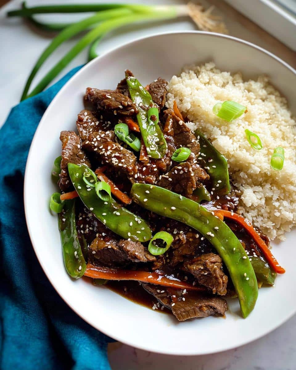 Close-up of Gluten-Free Beef Stir Fry with snap peas, carrots, and cauliflower rice.