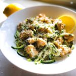 Close-up of Gluten-Free Chicken Alfredo served over zucchini noodles (zoodles), topped with Parmesan cheese.