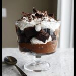 Close-up of a single serving of Gluten-Free Dairy-Free Brownie Trifle layered with chocolate pudding, brownie chunks, and whipped topping.