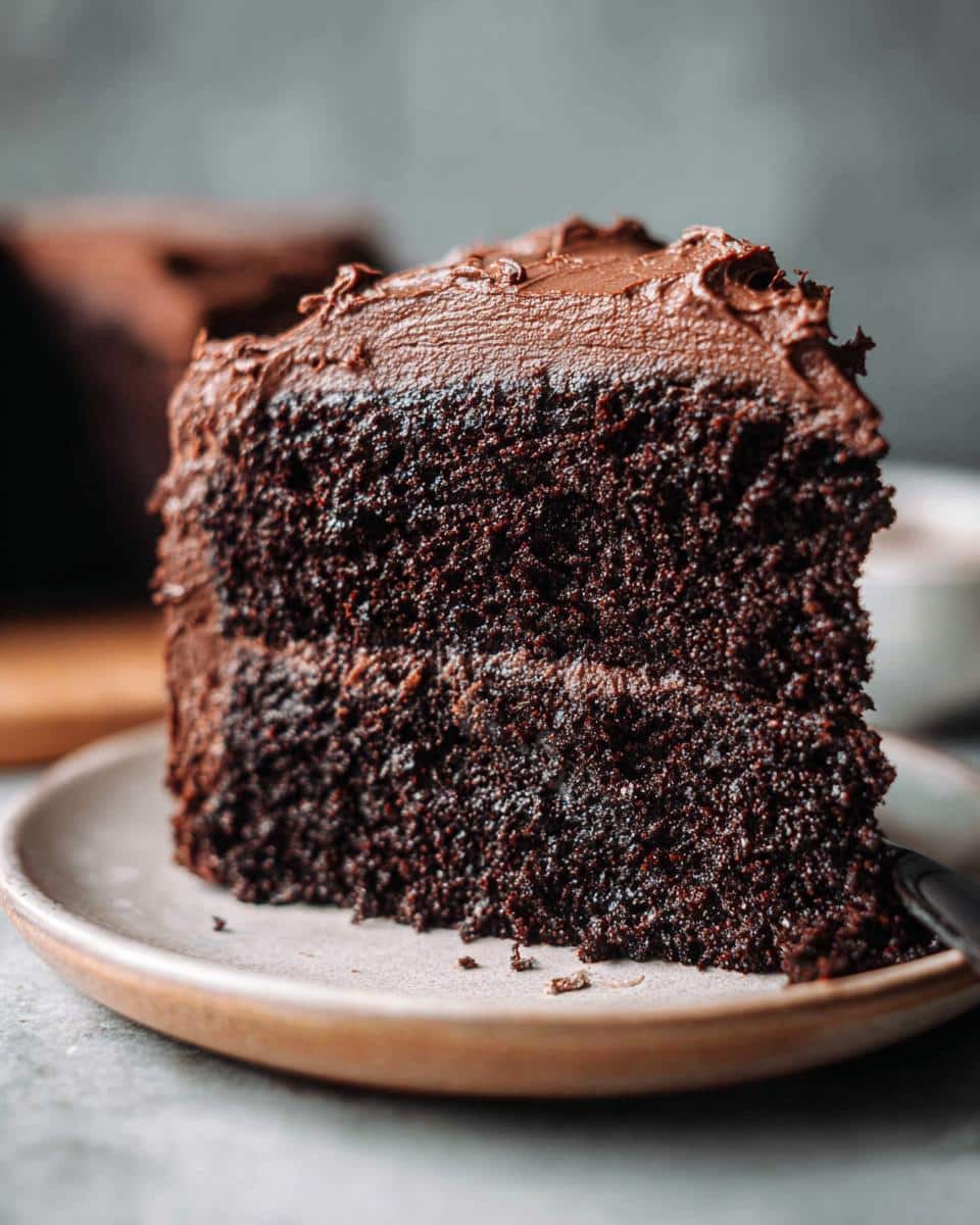 Close-up of a moist slice of Gluten-Free Dairy-Free Chocolate Cake with rich chocolate frosting.