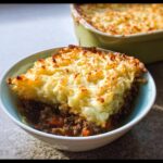 A serving of rich Gluten-Free Shepherd’s Pie in a bowl, featuring a thick layer of browned mashed potato topping over savory ground meat filling.