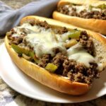 Close-up of a delicious Ground Beef Philly Cheesesteaks sandwich filled with seasoned ground beef, peppers, onions, and melted white cheese.