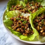 Two servings of savory Ground Chicken Lettuce Wraps filled with seasoned ground meat and topped with green onions.
