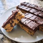 Close-up of stacked Healthy No-Bake Cookie Dough Bars with chocolate topping and sea salt flakes.